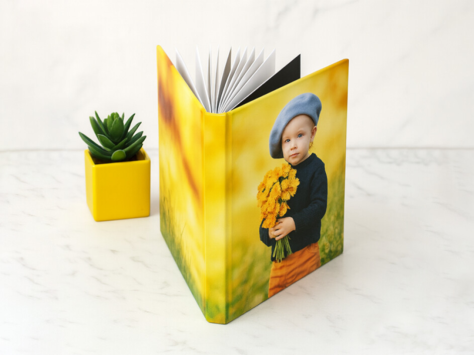 Álbum fotobook premium de lujo Mi Album infantil abierto con empastado fotográfico laminado en frío sobre mármol blanco.