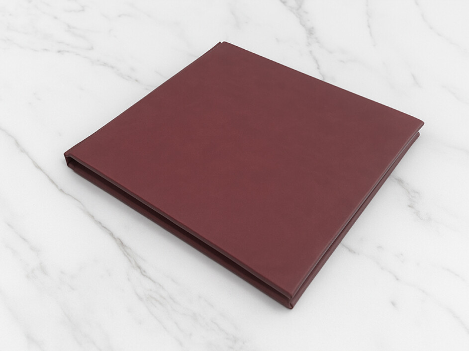 Fotobook Mi Album clásico premium cerrado, empastado en pasta dura vinil de lujo sobre superficie de mármol blanco.