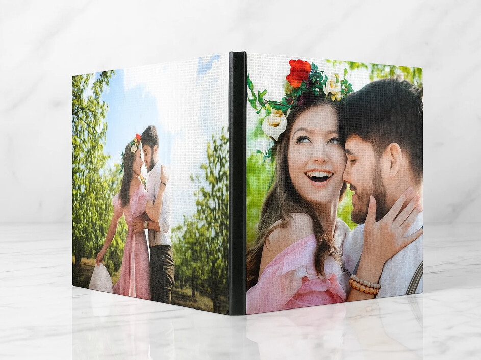 Fotobook con portada y contraportada impresas en canvas mate; vista frontal sobre mármol con lomo negro centrado. Textura de lienzo, colores vivos y empastado profesional de Mi Album para bodas, aniversarios y sesiones románticas.